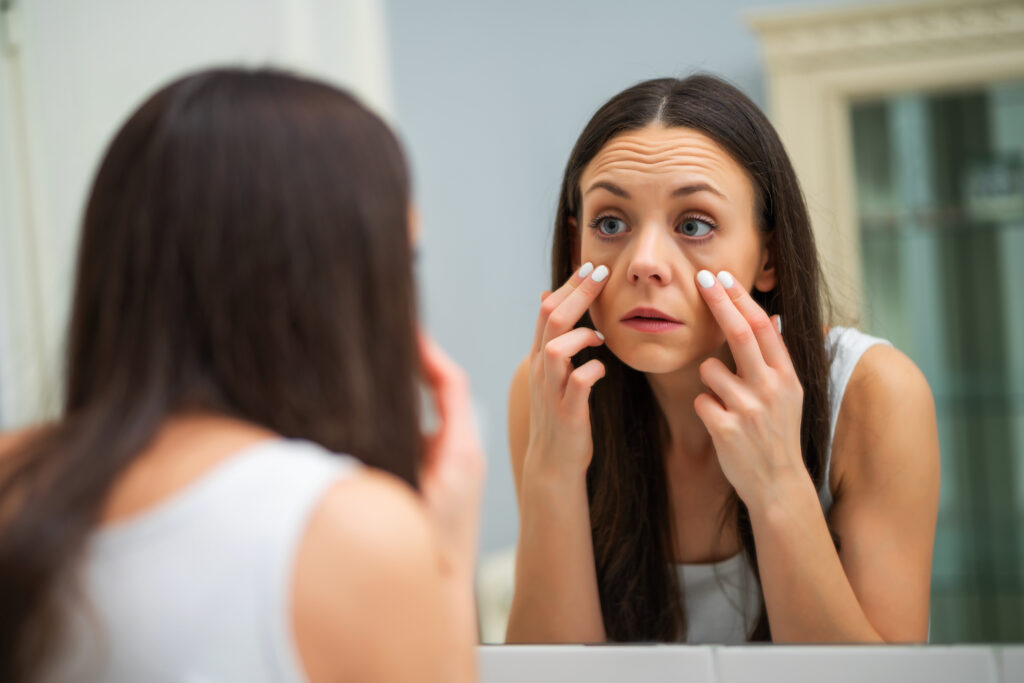Woman touching her undereye area in a mirror