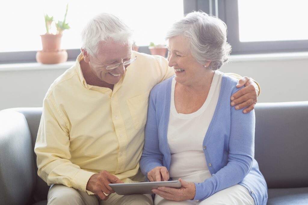 Older couple sitting on a couch at home with a tablet