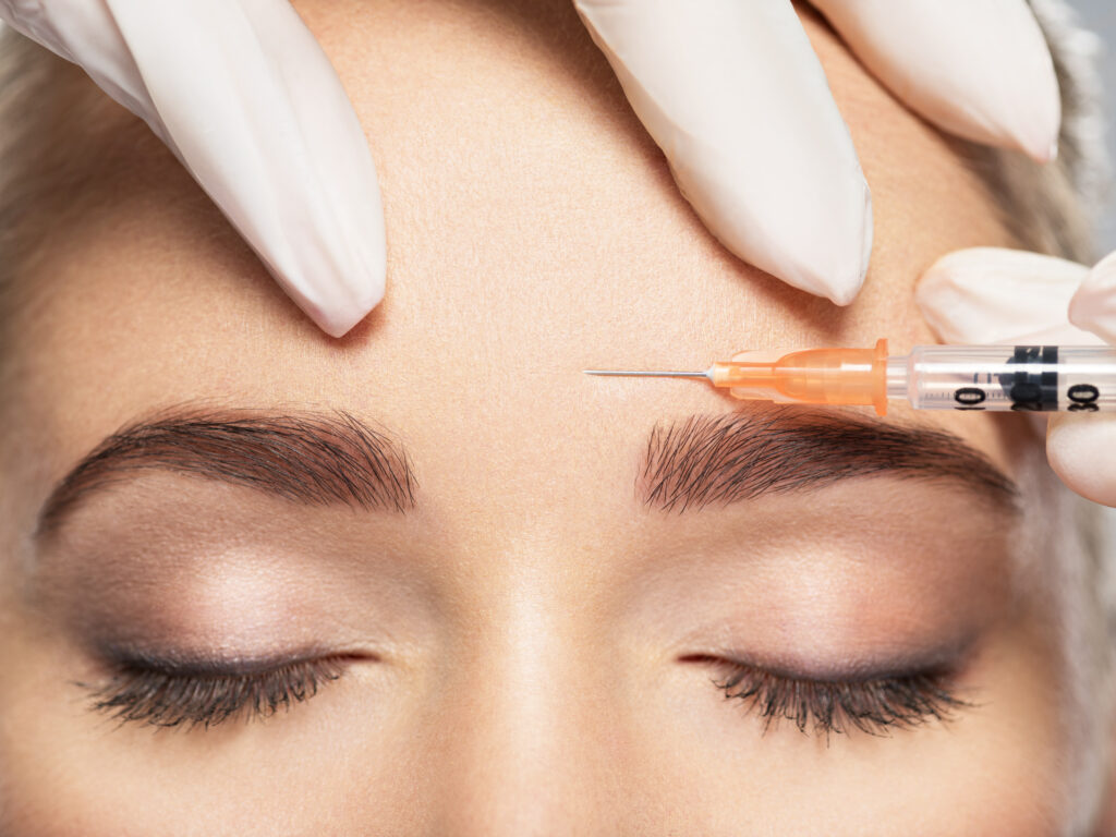 Woman getting cosmetic injection of botox near eyes.