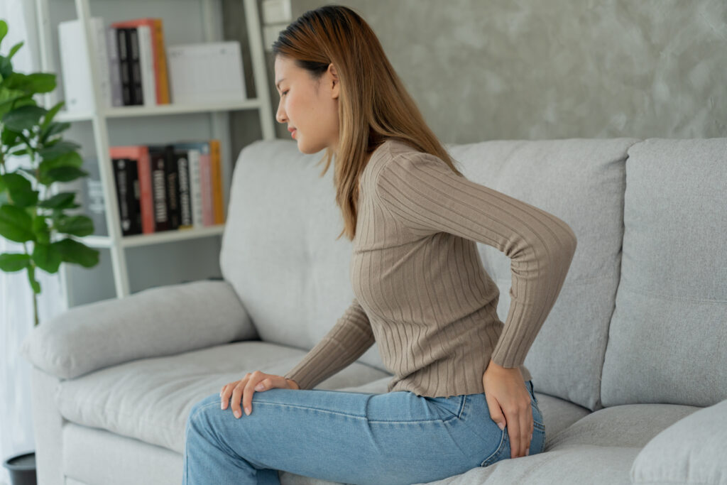 Woman hand holding her bottom due to abdominal pain and hemorrhoids