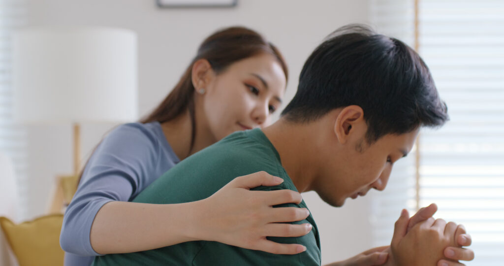 Dejected man sitting on the couch being comforted by a woman